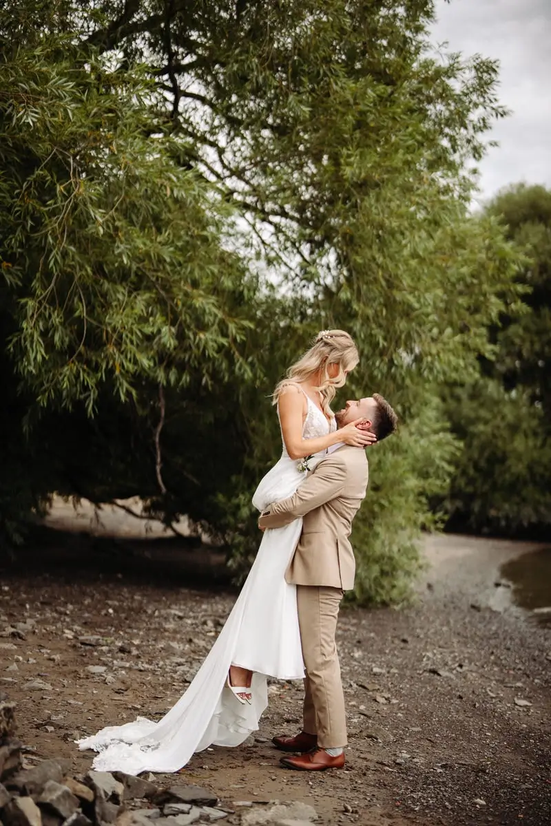 Le marié soulève la mariée sur la plage au Quai du Cap Blanc à Québec