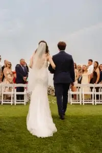 Bride going down the aisle with a rainbow over them at the Manoir Richelieu's golf course
