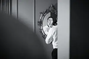 Groom getting ready and looking at a mirror at the Fairmont Chateau Frontenac