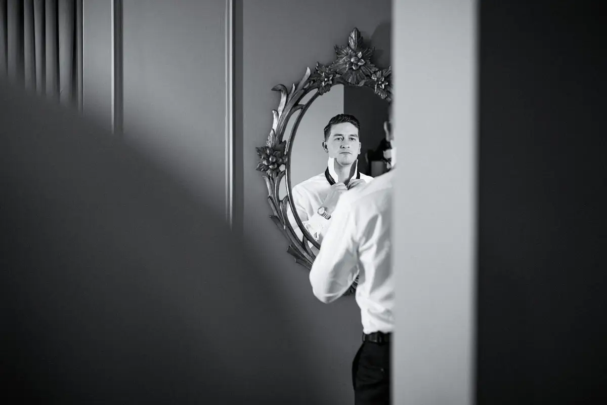 Groom getting ready and looking at a mirror at the Fairmont Chateau Frontenac