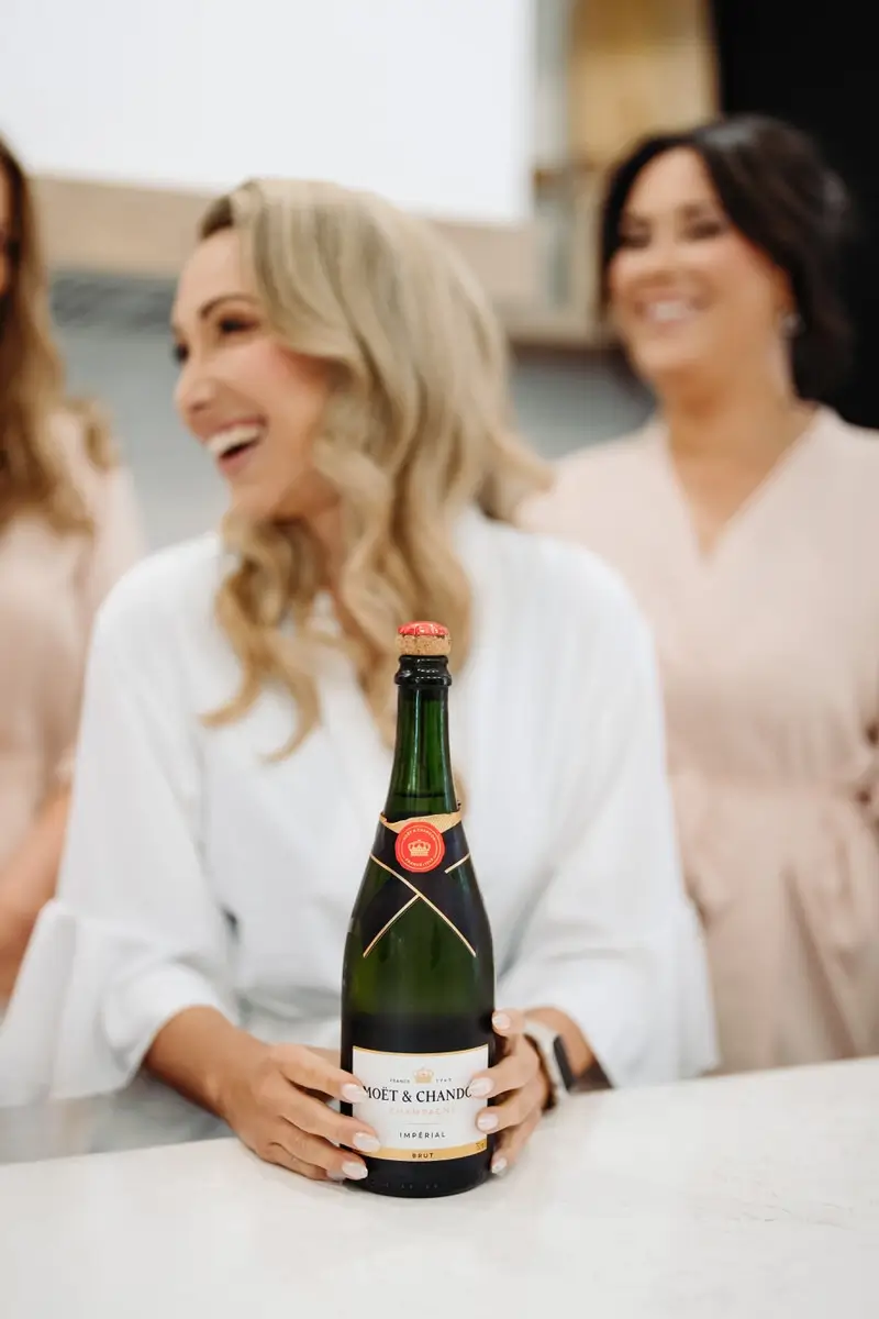 La mariée se prépare et tient une bouteille de champagne Moët & Chandon