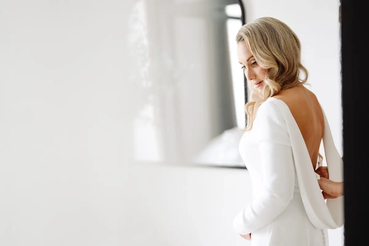 La mariée enfile sa robe dans un lumière divine