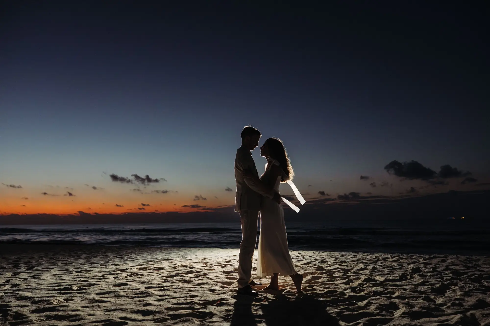 Silhouette d'un homme et une femme sur la plage au lever du soleil
