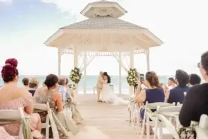 Les mariés s'embrassent au gazebo sur la plage du Bahia Principe Explore Punta Cana