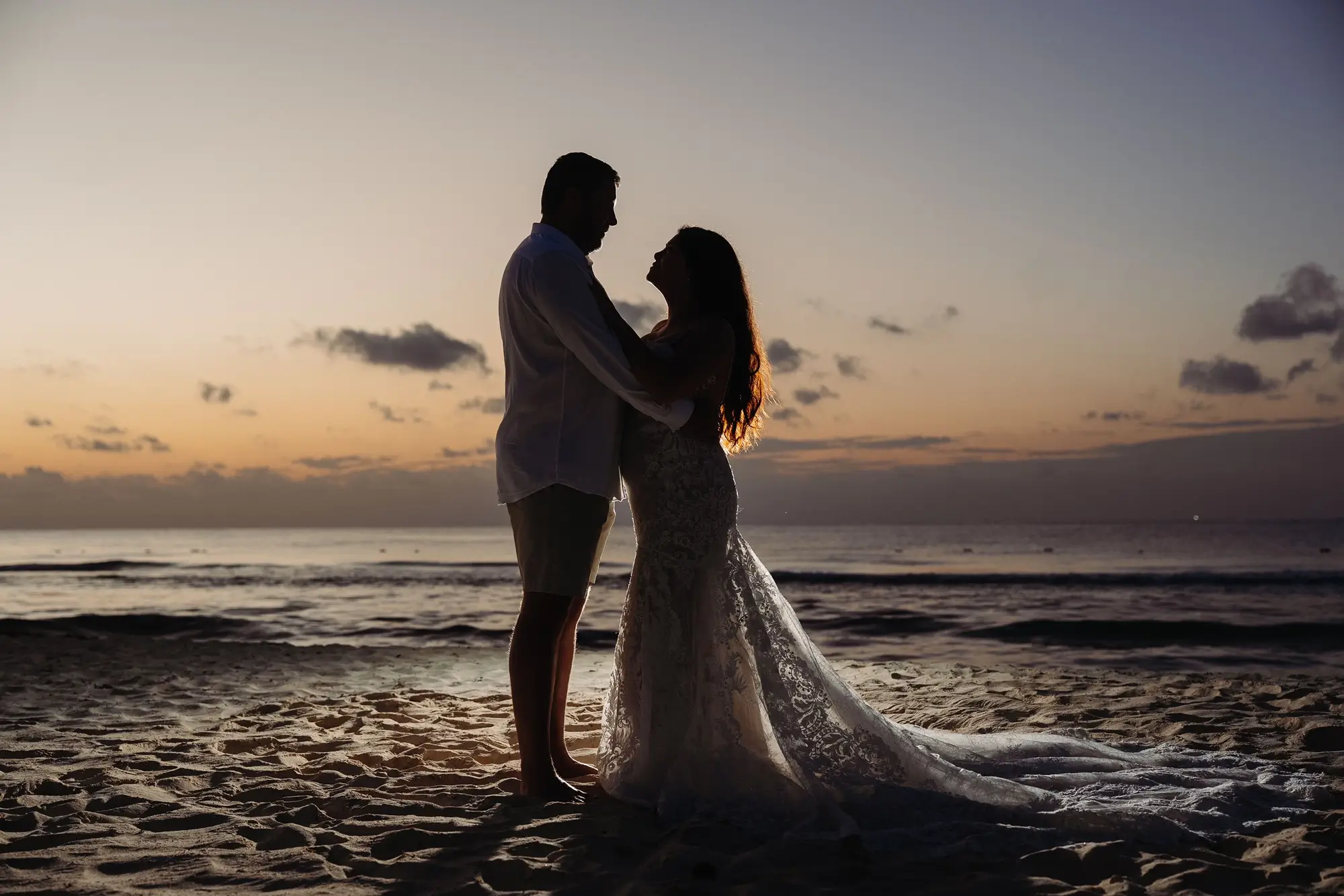 Silhouette de 2 mariés au lever du soleil sur la plage