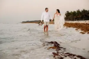 Un couple de mariés marche sur la plage au lever du soleil