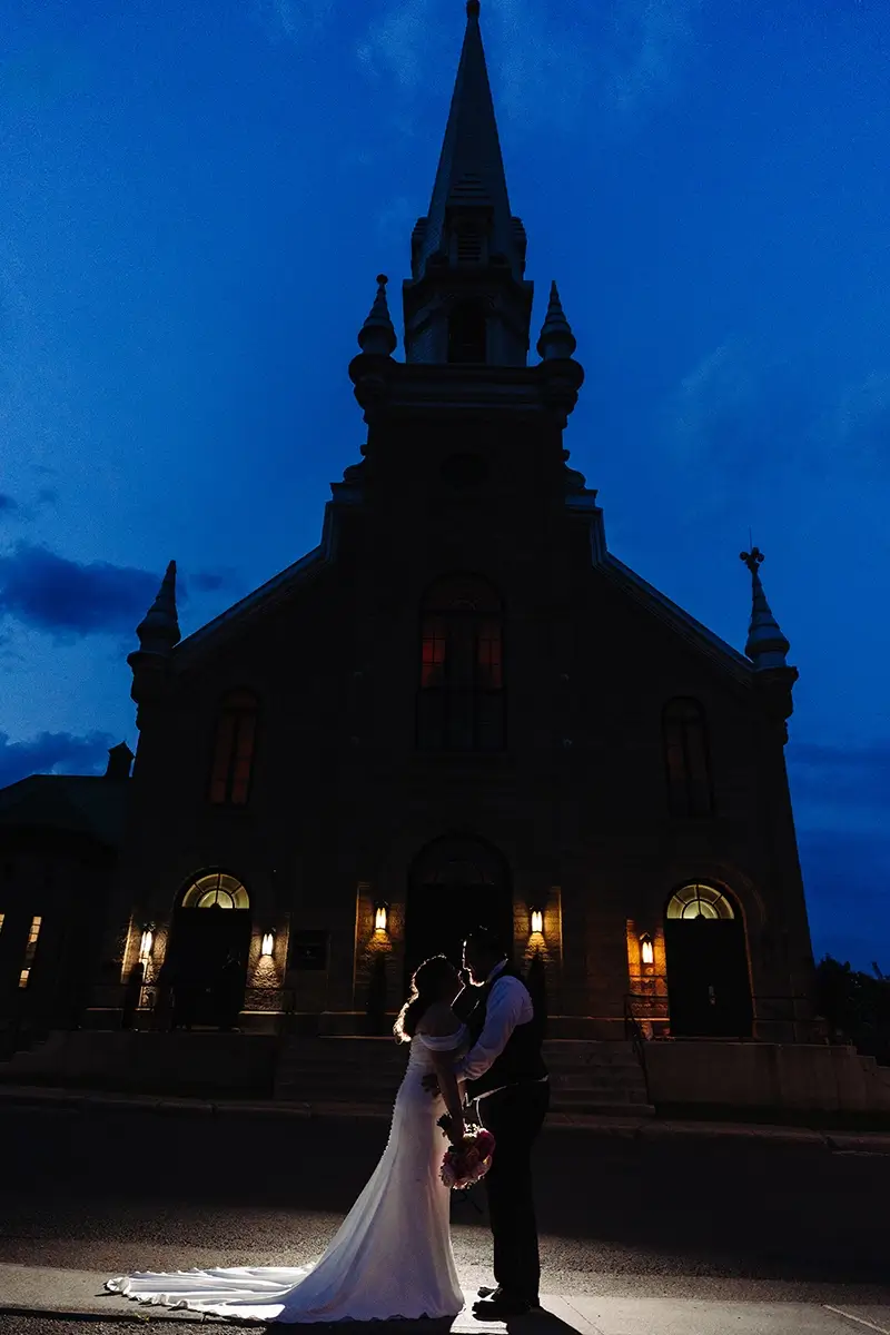 Silhouette of bride and groom in front of a church