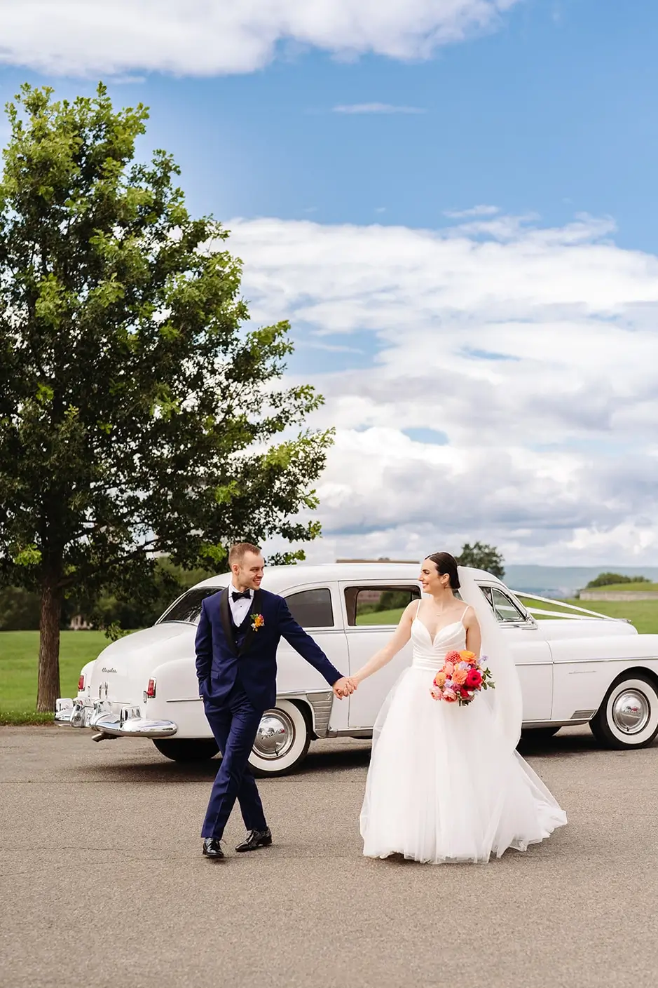 bride and groom walking by an old antique white car