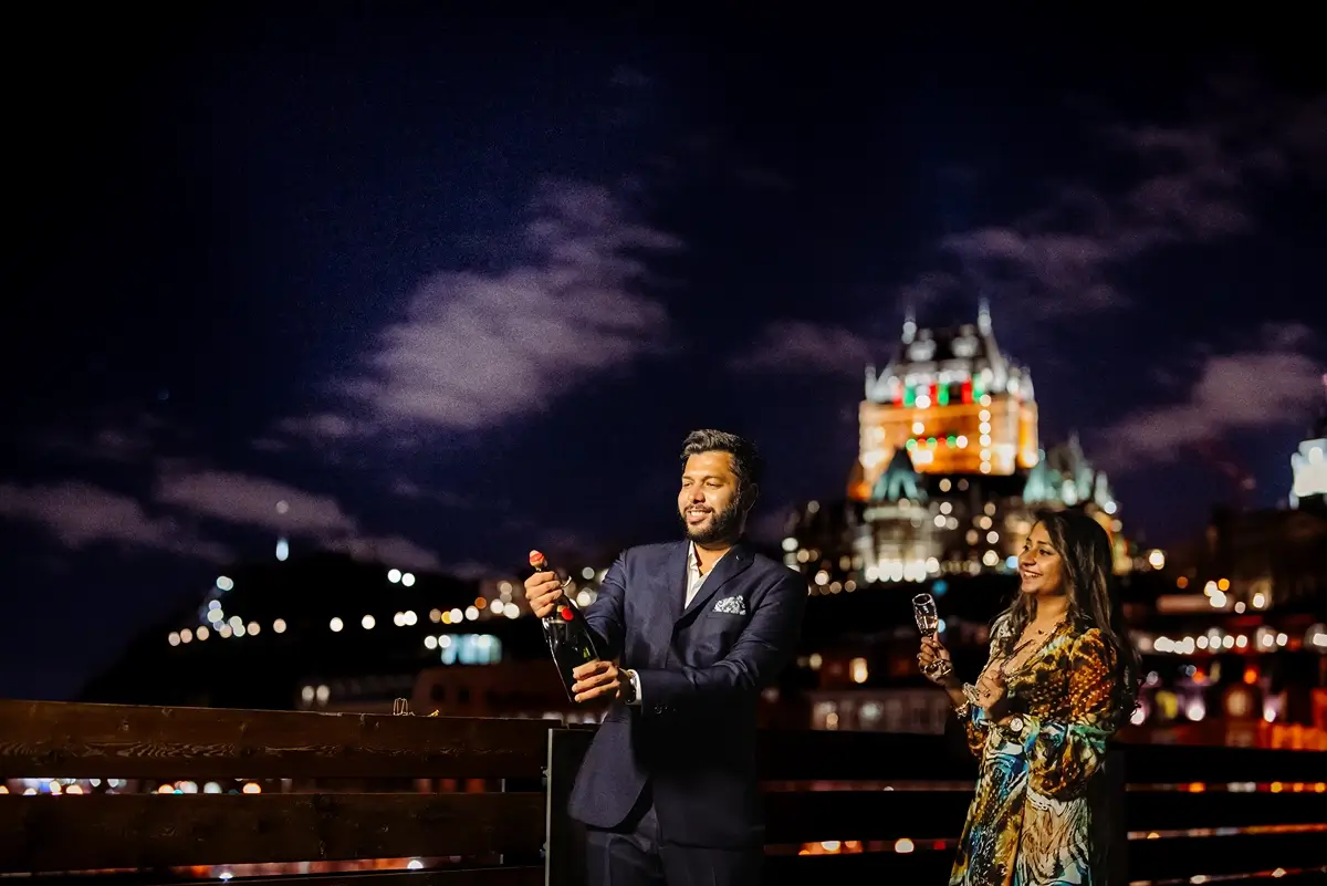 Couple pop a Champagne bottle in front of the Chateau Frontenac
