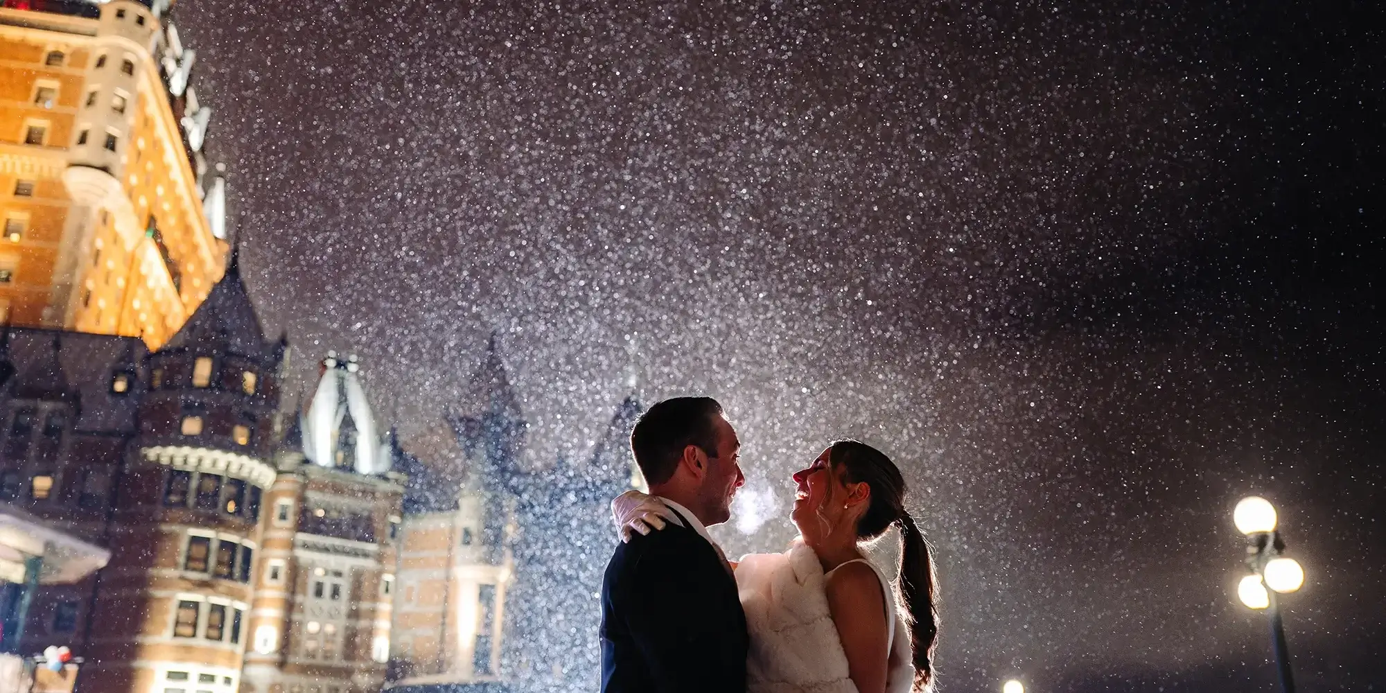 Quebec-city-wedding-photographer-chateau-frontenac Bride and groom under the snow in front of the Fairmont Chateau Frontenac